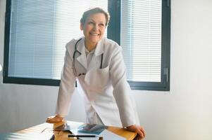 Portrait of middle age female doctor is wearing a white doctor's coat with a stethoscope around her neck. photo