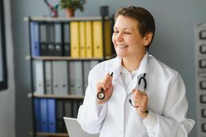 Portrait of middle age female doctor is wearing a white doctor's coat with a stethoscope around her neck. photo