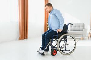 young man trying to get up from wheelchair at home, full length. Impaired black man attempting to stand, exercising his legs indoors, copy space. photo