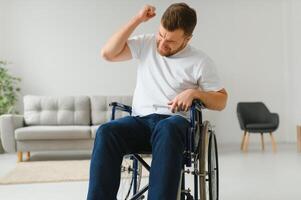 Young sad man in a wheelchair at home photo