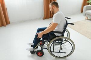 disabled man at home tries to get to his feet in a wheelchair. The concept of rehabilitation after injuries and car accidents photo