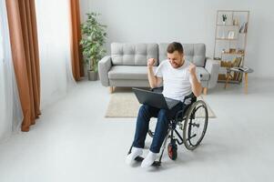 Man in wheelchair working on laptop in living room. photo