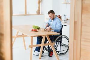 man in a wheelchair cuts vegetables in the kitchen photo