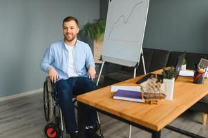 un hombre en un silla de ruedas es trabajando en un oficina. el concepto de trabajo de personas con discapacidades foto