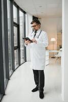 Portrait of healthcare worker. Image of senior male doctor wearing lab coat and standing at private clinic photo