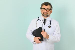 Senior doctor man wearing stethoscope and medical coat oveer blue background photo