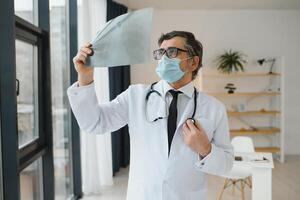 Doctor wearing mask and looking at chest x-ray. photo