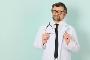 Senior doctor man wearing stethoscope and medical coat over blue background. Cheerful expression photo