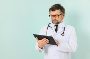 sonriente médico mayor médico con un estetoscopio. en un azul antecedentes. el concepto de de la humanidad victoria terminado enfermedad foto