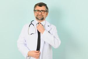 Senior doctor man wearing stethoscope and medical coat over blue background. Cheerful expression photo