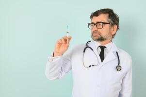 male doctor holding syringe, isolated blue background. photo