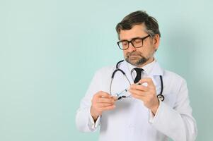 Vaccination against coronavirus. Testing COVID-19 vaccines. A male doctor fills a syringe the with a COVID-19 vaccine on a blue background. Doctor's hands hold a syringe close-up photo