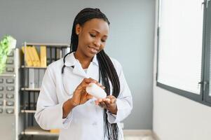 cuidado de la salud y médico concepto - africano médico con ampolla paquetes de pastillas foto