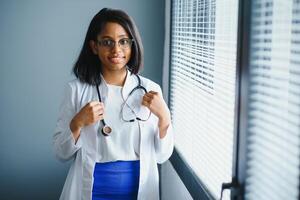 Portrait Of Smiling Female Doctor Wearing White Coat With Stethoscope In Hospital Office. photo