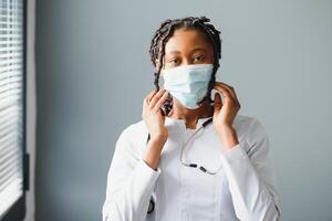 medicine, profession and healthcare concept - close up of african female doctor or scientist in protective facial mask photo