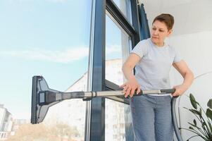 beautiful senior woman cleaning window glass. photo