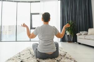 Middle-aged woman doing yoga at home for stretching and being healthy. photo