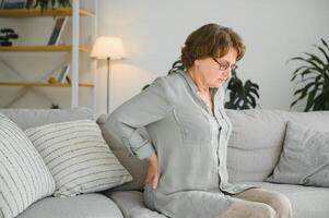 mature lady sitting on bed and touching her back, radiculitis and pain photo