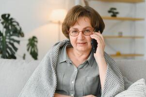 hermoso abuela hablando en el teléfono a hogar. foto