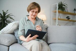 Smiling senior woman at home connected on internet photo