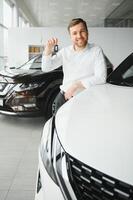 Yes, that's my new car. Customer in car dealership. Young man with keys in hand. photo