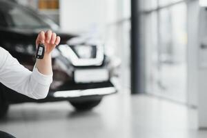 Man's hand holding modern car keys ready for rental. car buyer's hand with keys photo