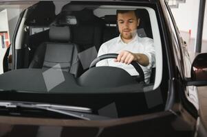 Handsome businessman driving car before buying photo