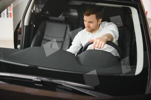 Handsome businessman driving car before buying photo