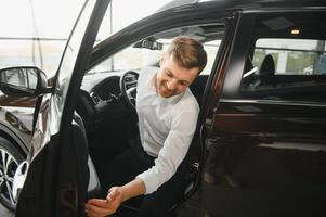 Handsome businessman driving car before buying photo