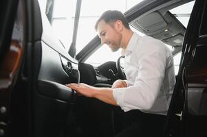 hombre adulto cliente masculino comprador cliente elige auto quiere a comprar nuevo automóvil toque cheque coche en sala de exposición vehículo salón concesión Tienda motor espectáculo interior. ventas concepto foto