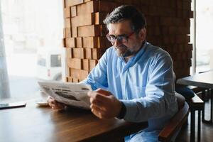 periódico en el Mañana. mayor empresario a su oficina montando periódicos foto