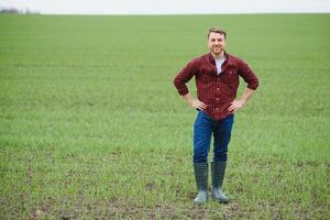 Handsome farmer. Young man walking in green field. Spring agriculture. photo
