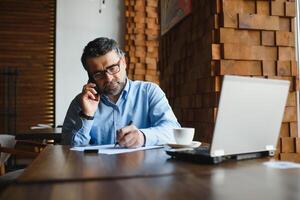 negocio, tecnología y personas concepto , mayor empresario con ordenador portátil computadora Bebiendo café a moderno cafetería. foto