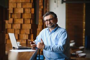 negocio, tecnología y personas concepto , mayor empresario con ordenador portátil computadora Bebiendo café a moderno cafetería. foto