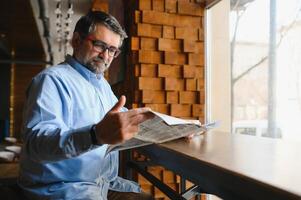 Newspaper in the morning. Senior businessman at his office riding newspapers. photo