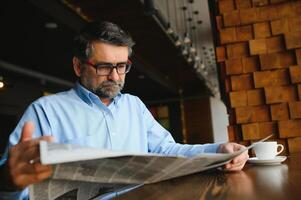 Newspaper in the morning. Senior businessman at his office riding newspapers. photo