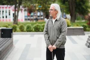 mayor hombre camina con un caña en un ciudad primavera parque. foto