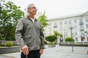 Portrait of senior man holding walking stick while resting in park. photo