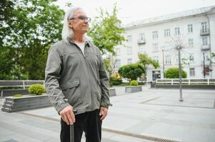 Elderly man walks with a cane in a city spring park. photo