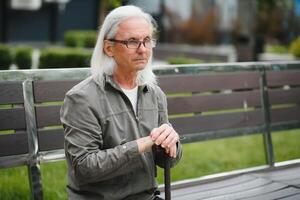 Old gray-haired man rest on the bench in summer park photo