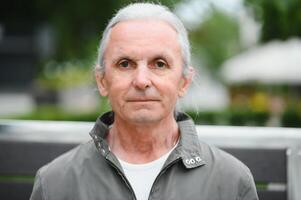 Old gray-haired man rest on the bench in summer park photo