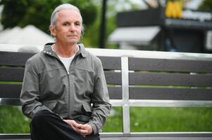 Senior grey-haired man standing at the city. photo
