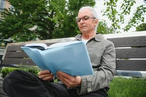 Old gray-haired man rest on the bench in summer park photo