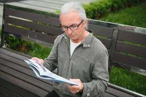 Old gray-haired man rest on the bench in summer park photo