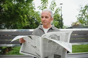 Old gray-haired man rest on the bench in summer park photo