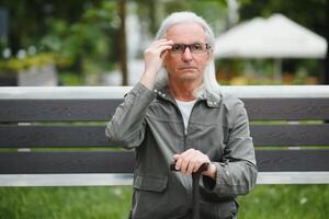 Old gray-haired man rest on the bench in summer park photo