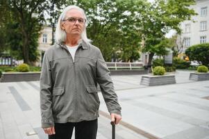 Elderly man walks with a cane in a city spring park. photo