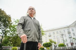 Portrait of senior man holding walking stick while resting in park. photo