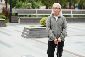 Portrait of senior man holding walking stick while resting in park. photo