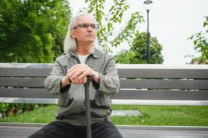 mayor hombre camina con un caña en un ciudad primavera parque. foto